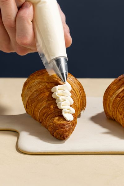 Piping cream filling onto a croissant