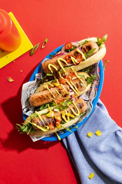 Farmer's sausage hotdogs with mustard on a bold red backdrop
