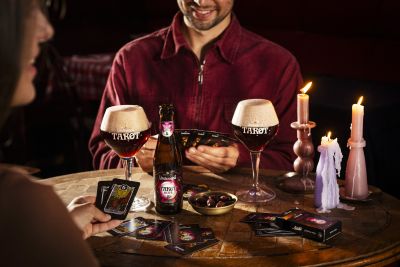 Friends playing a tarot card game with Lindemans beer by candlelight