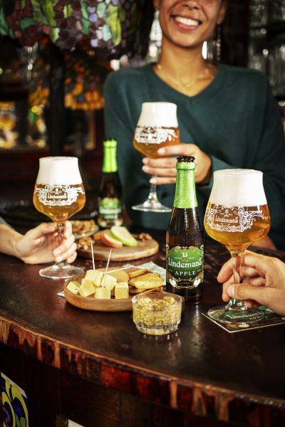 Friends enjoying Lindemans apple beer at a cafe bar