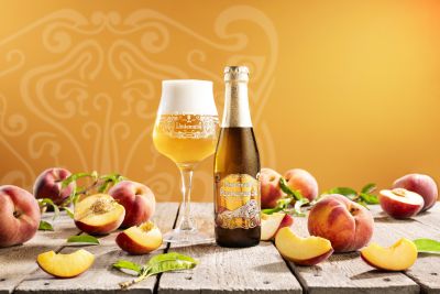 Lindemans Pecheresse peach beer bottle and glass with fresh peaches