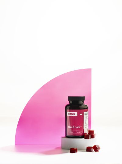 Supplement bottle styled with pink graphic backdrop