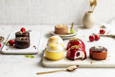 Assorted individual mini cakes and tarts on a marble board